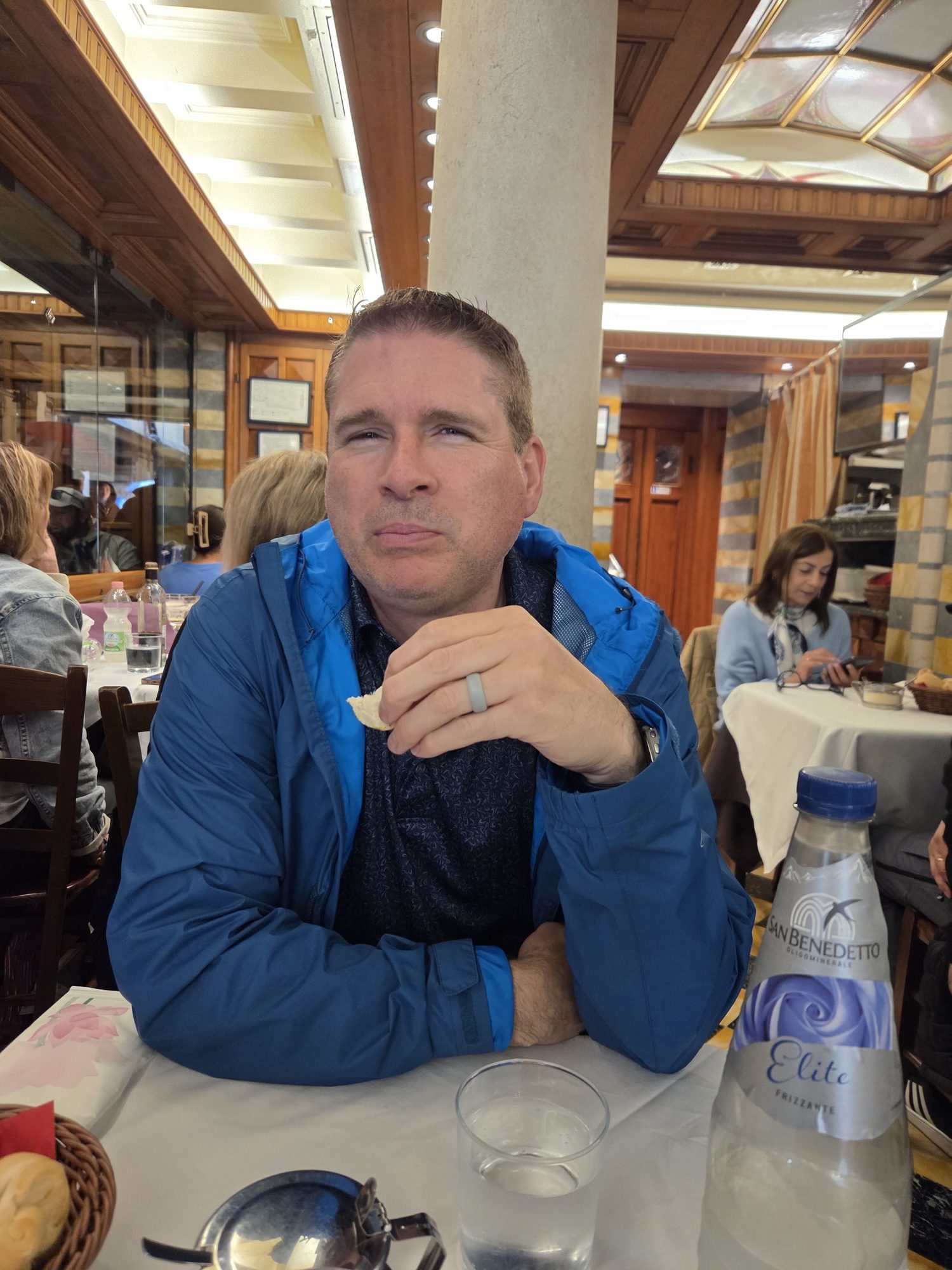 Kyle at a restaurant table with San Benedetto mineral water, mid-bite during a Venice lunch