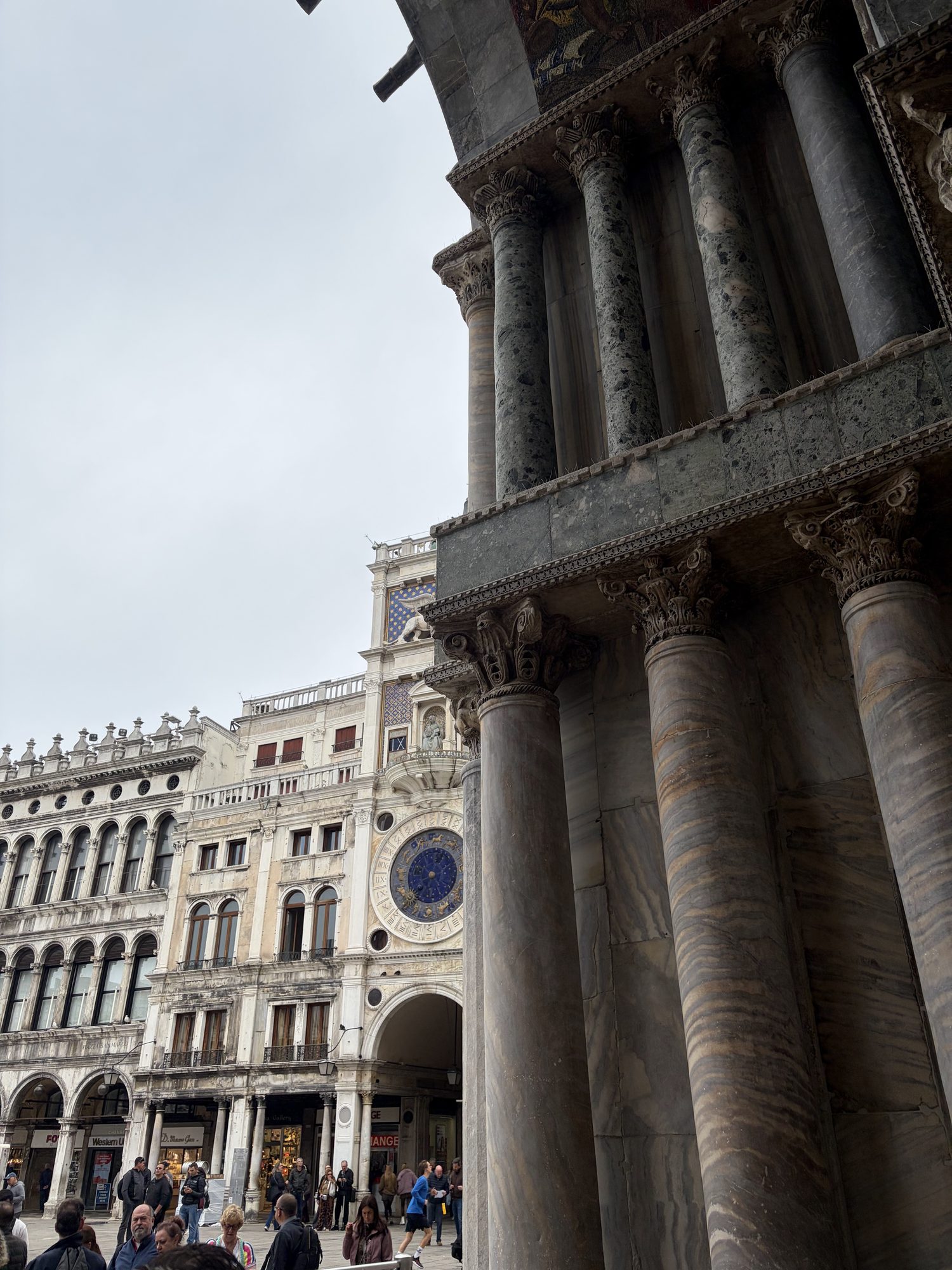 St Mark's Basilica marble columns in the foreground with the Torre dell'Orologio clocktower across Piazza San Marco