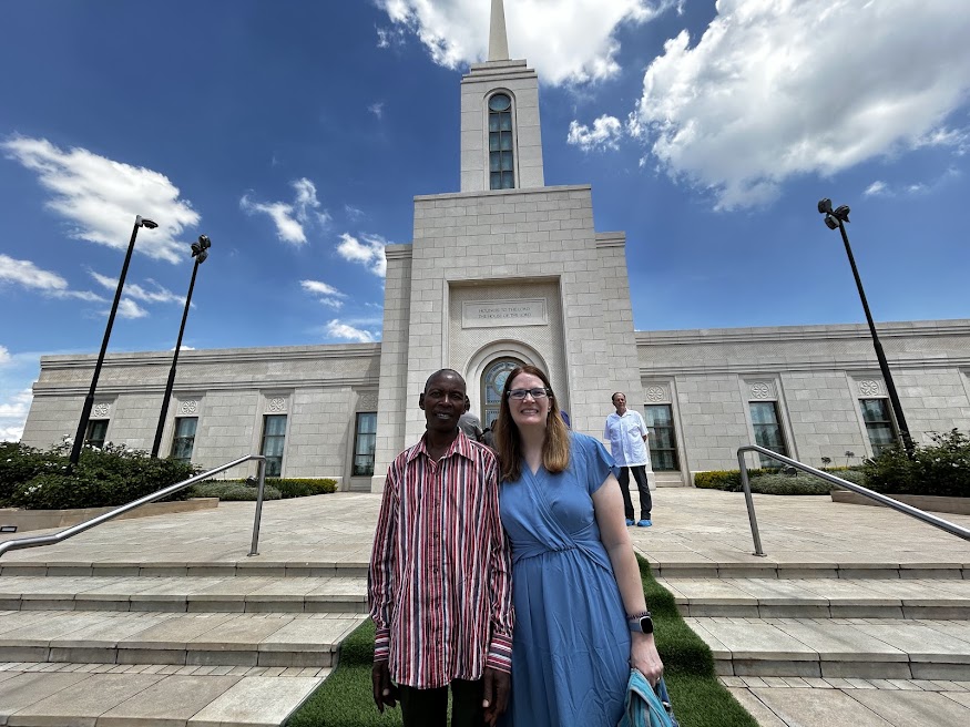 Two people standing on the steps of the Nairobi Kenya Temple under a bright blue sky