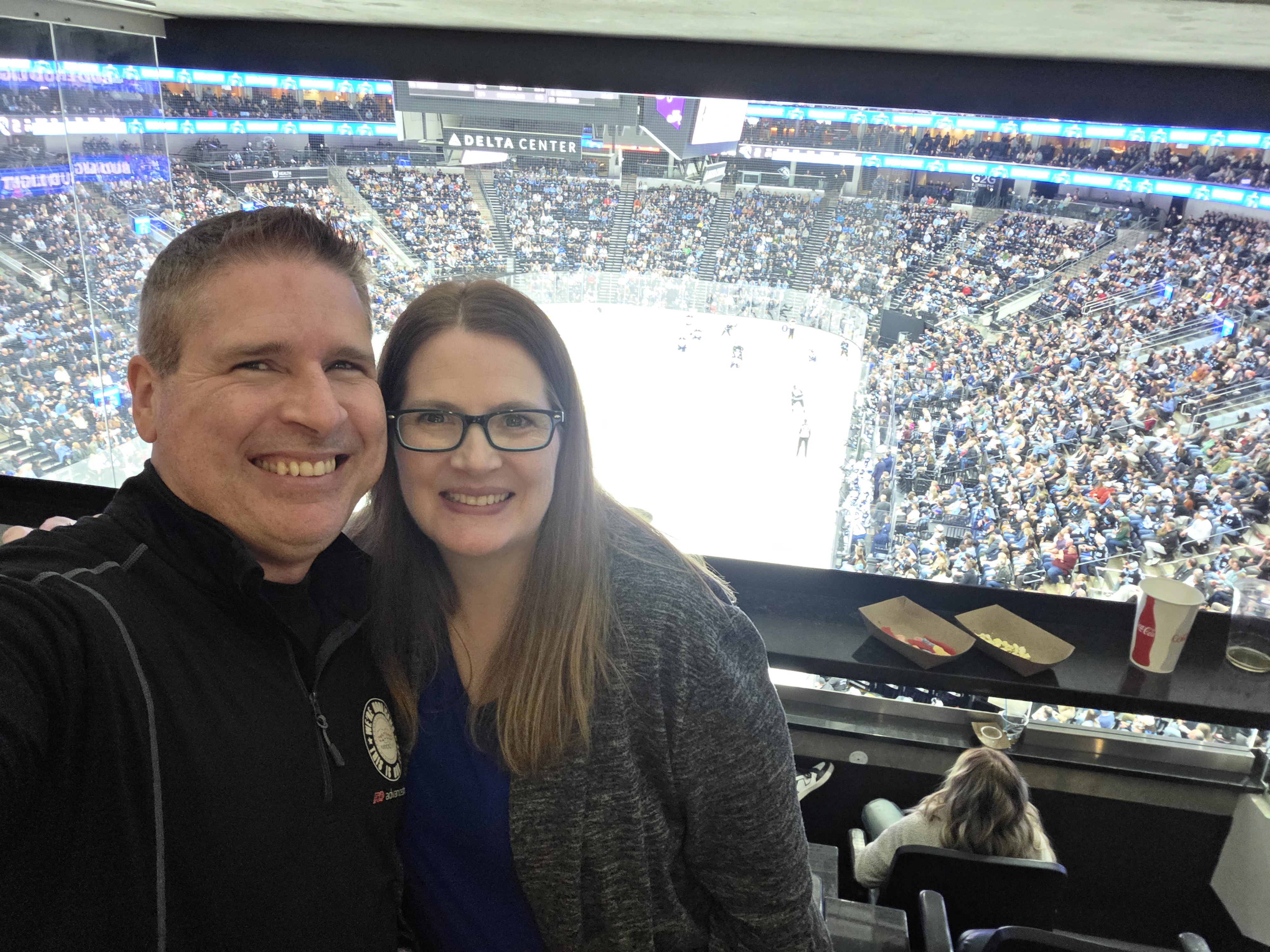 Kyle and Mandy smiling together at a Utah Mammoth hockey game in an arena suite